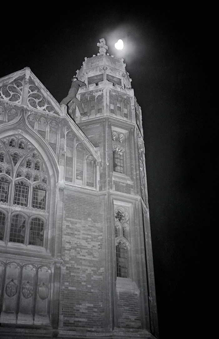 A climber on Cambridge stonework at night